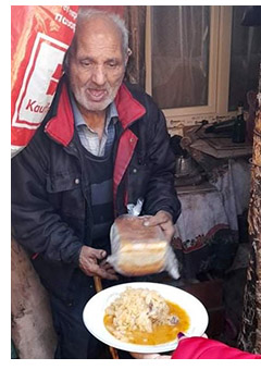 An elderly man receiving food from the soup kitchen project